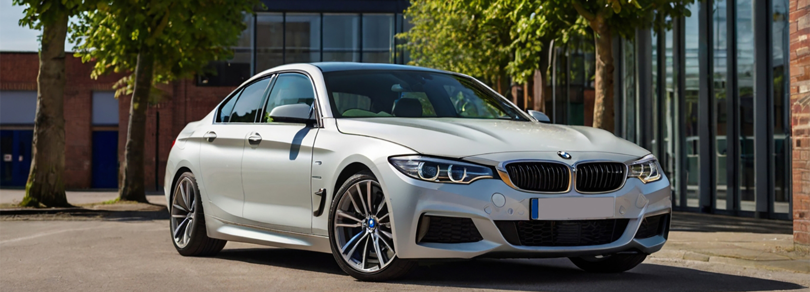 A Sleek BMW M4 Gran Coupe luxury sedan car in metallic silver, parked in front of a building